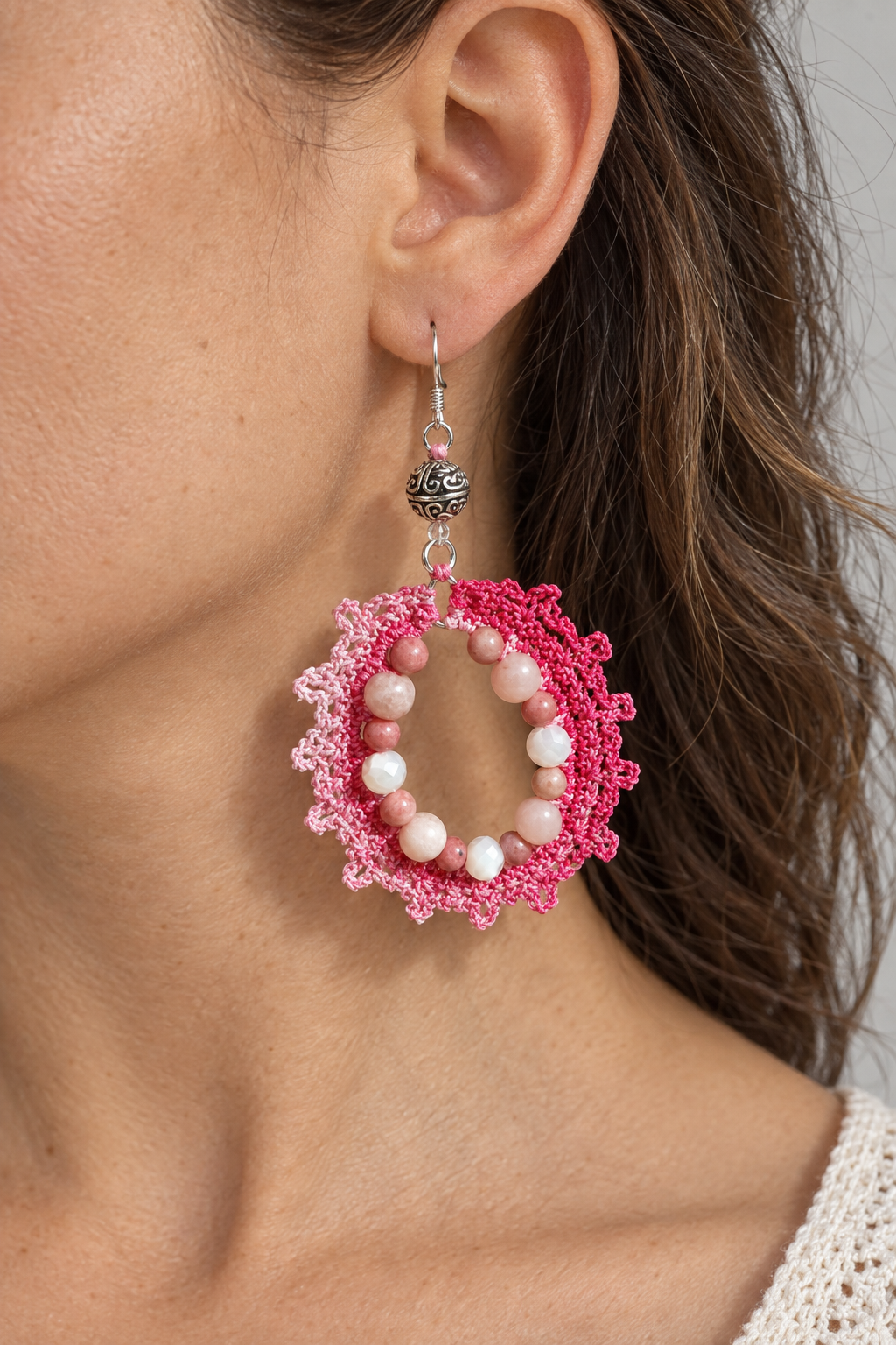 Visuel illustratif d’une boucle rose en coton crocheté et perles roses portée à l’oreille
