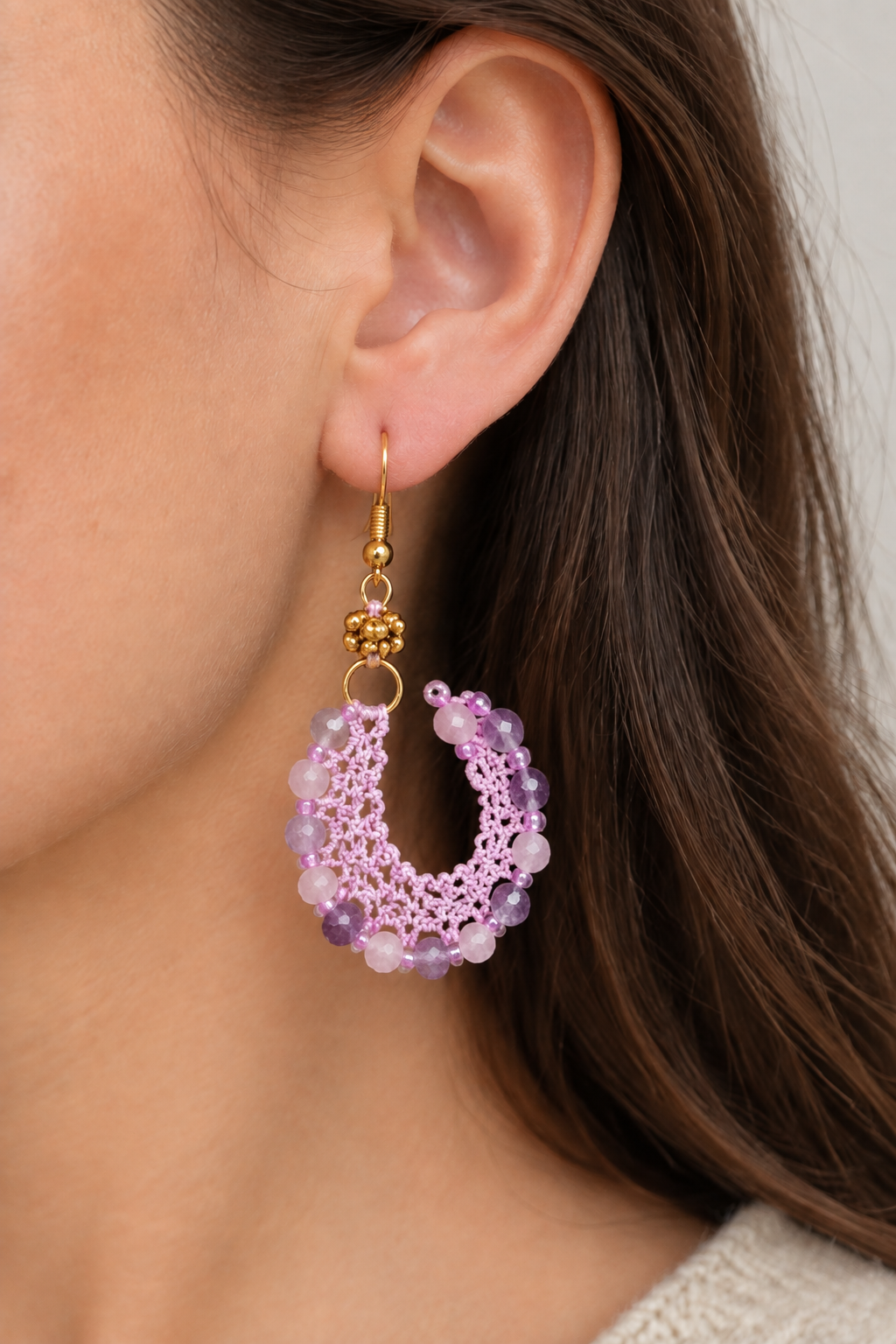 Petite boucle d’oreille portée en coton violet clair, côté libre recourbé, perles de kunzite et fluorine