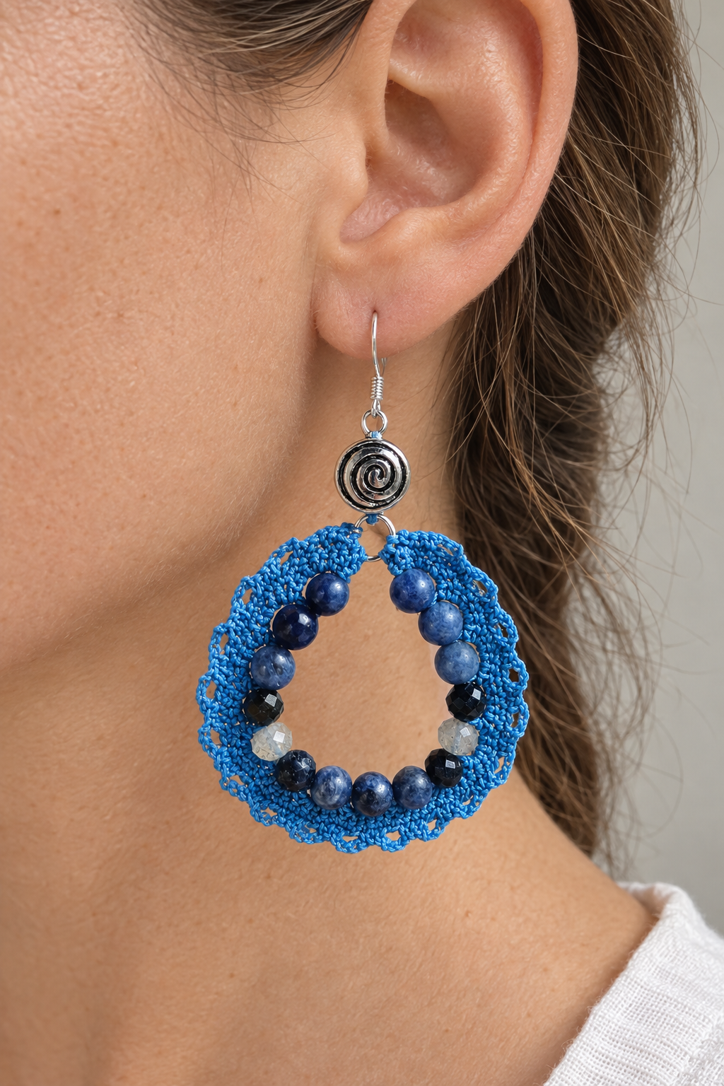 Visuel illustratif d’une boucle bleue en coton crocheté, sodalite, saphir et labradorite portée à l’oreille